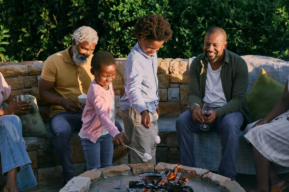 Family roasting marshmallows around a backyard fire pit.